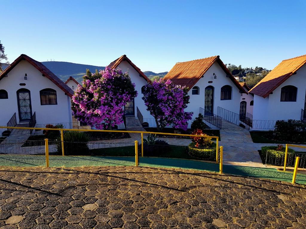 een rij huizen met paarse bloemen voor hen bij Hotel Akropolis in Serra Negra