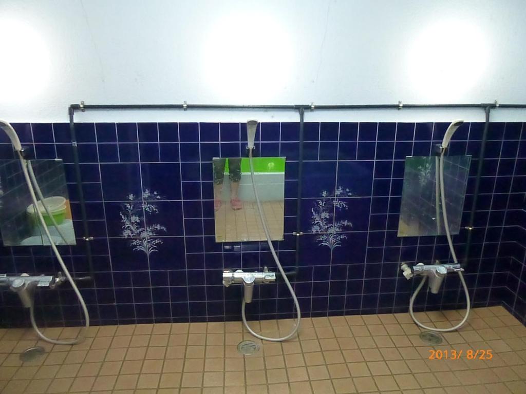 a bathroom with three mirrors and a blue tiled wall at Hotel Diamond in Osaka