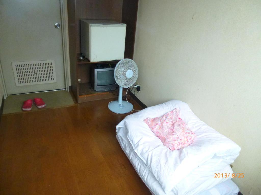 a room with a bed with a fan and a tv at Hotel Diamond in Osaka