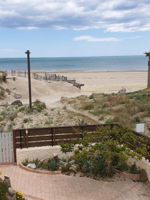 Elle offre une vue sur une plage avec une clôture et l'océan. dans l'établissement Les pieds dans le sable, au Cap d'Agde