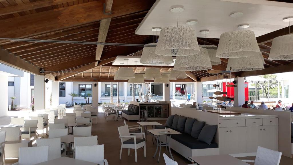 a restaurant with white chairs and tables and chandeliers at Hipotels Barrosa Park in Chiclana de la Frontera