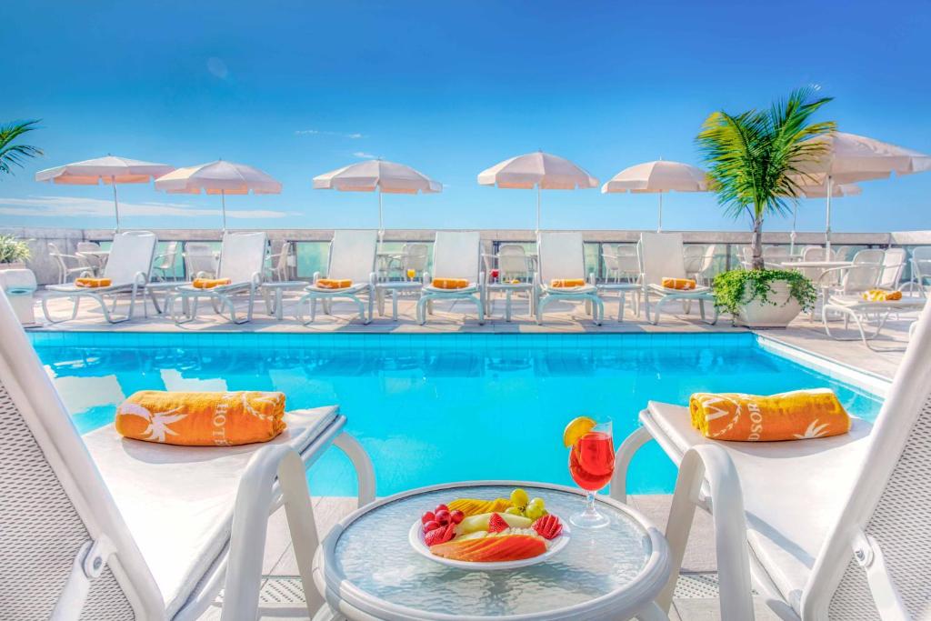 uma piscina de resort com cadeiras e uma mesa com fruta em Windsor Excelsior Copacabana no Rio de Janeiro