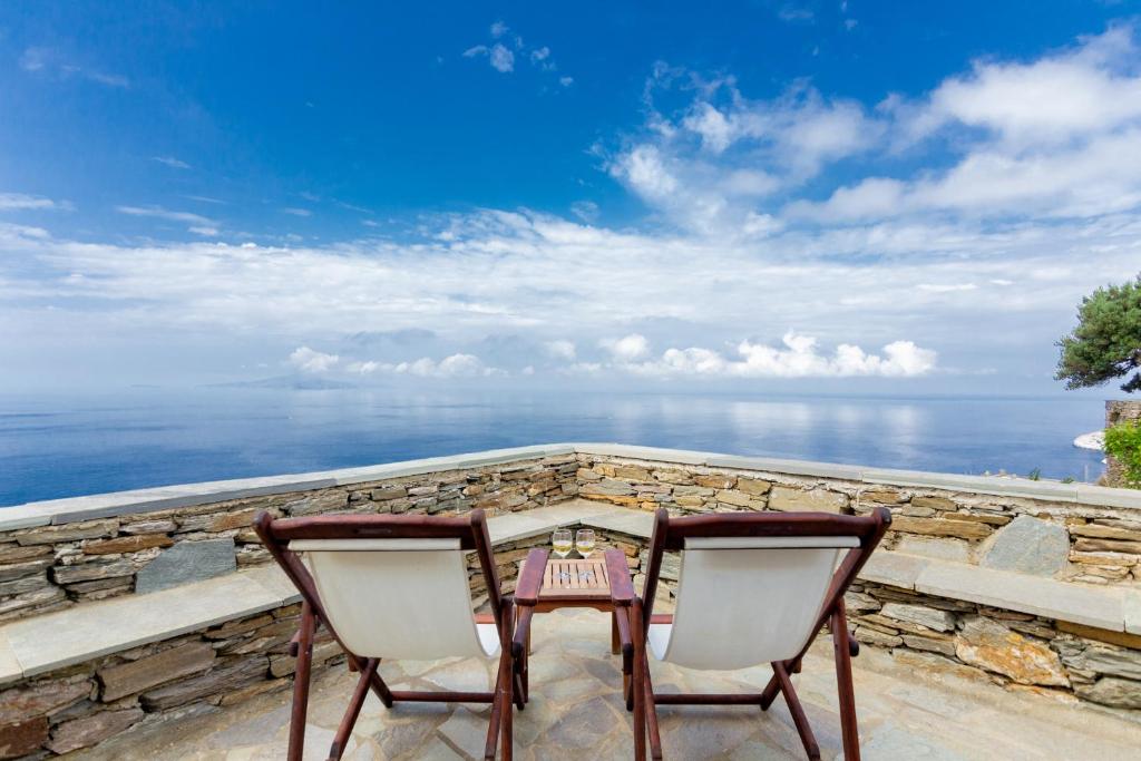 d'une table et de deux chaises sur un balcon donnant sur l'océan. dans l'établissement Andros Serenity Adults Only Residences, à Episkopión