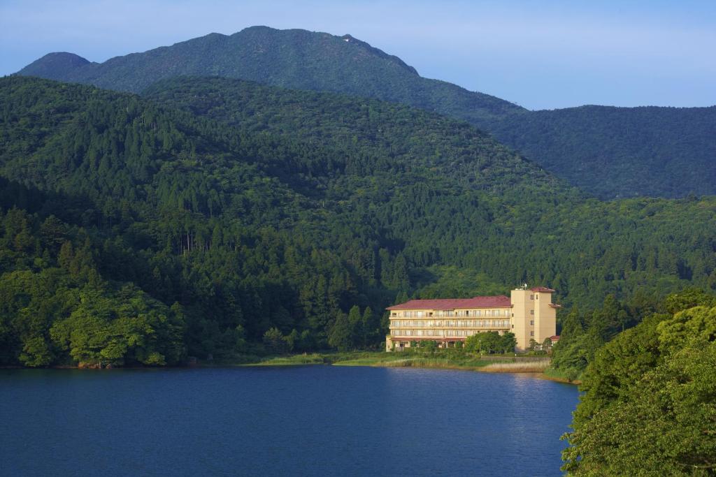 a building on the side of a lake with mountains at Azumaen in Unzen