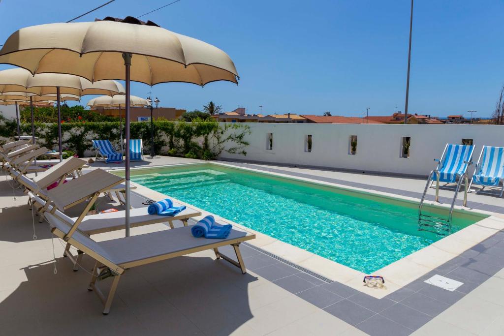 - une piscine avec des chaises et un parasol dans l'établissement MareinSicilia: Talia Residence, à Sampieri