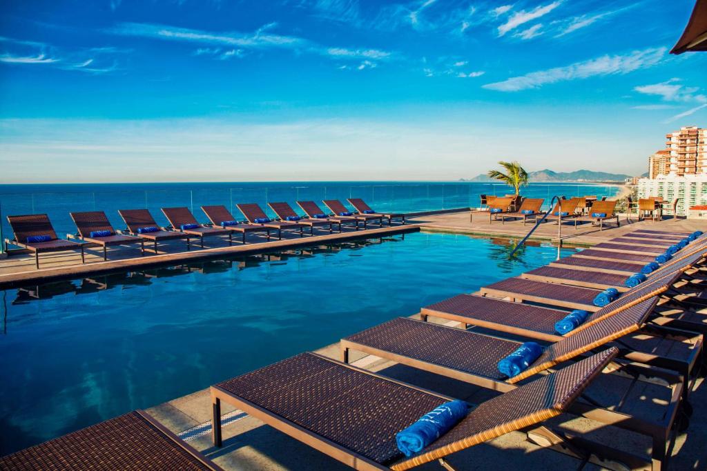 een zwembad met ligstoelen en de oceaan bij Windsor Oceanico Hotel in Rio de Janeiro