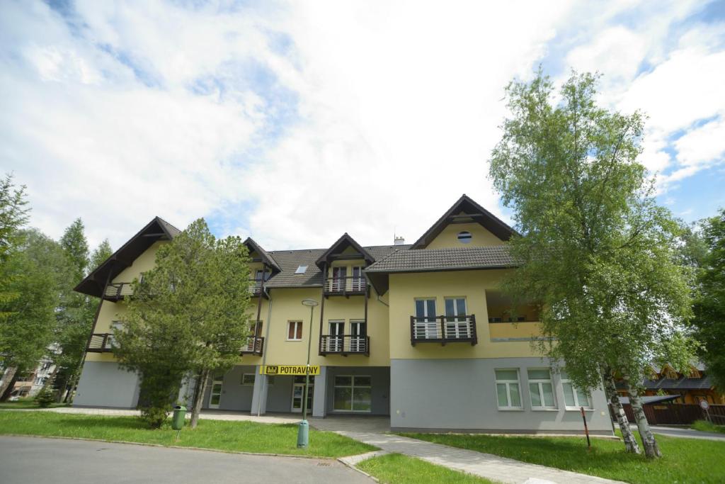 ein Haus in einem Vorort mit Bäumen davor in der Unterkunft Apartmán Lomnica in Tatranská Lomnica
