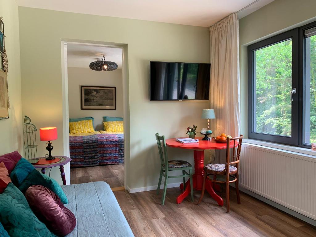 a living room with a table and a bed at B&B de Ruijsvogel in De Koog