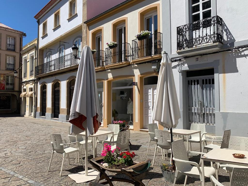 un groupe de tables et de parasols devant un bâtiment dans l'établissement Apartamento Noia Centro Izqda, à Noia