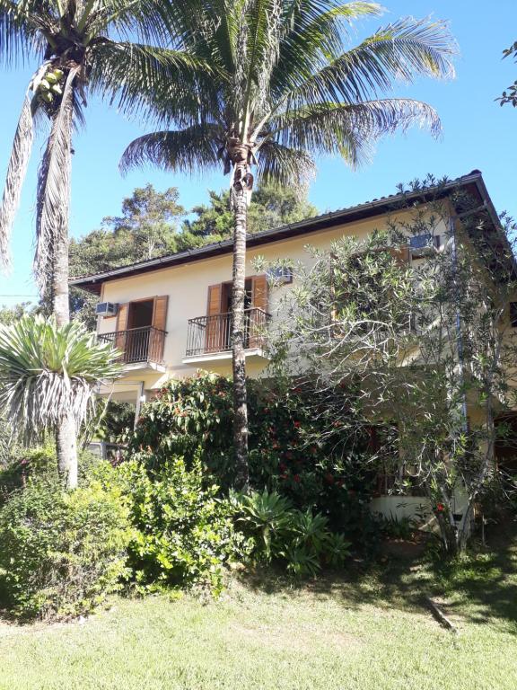 una casa con palmeras delante en Pousada da Figueira, en Conservatória