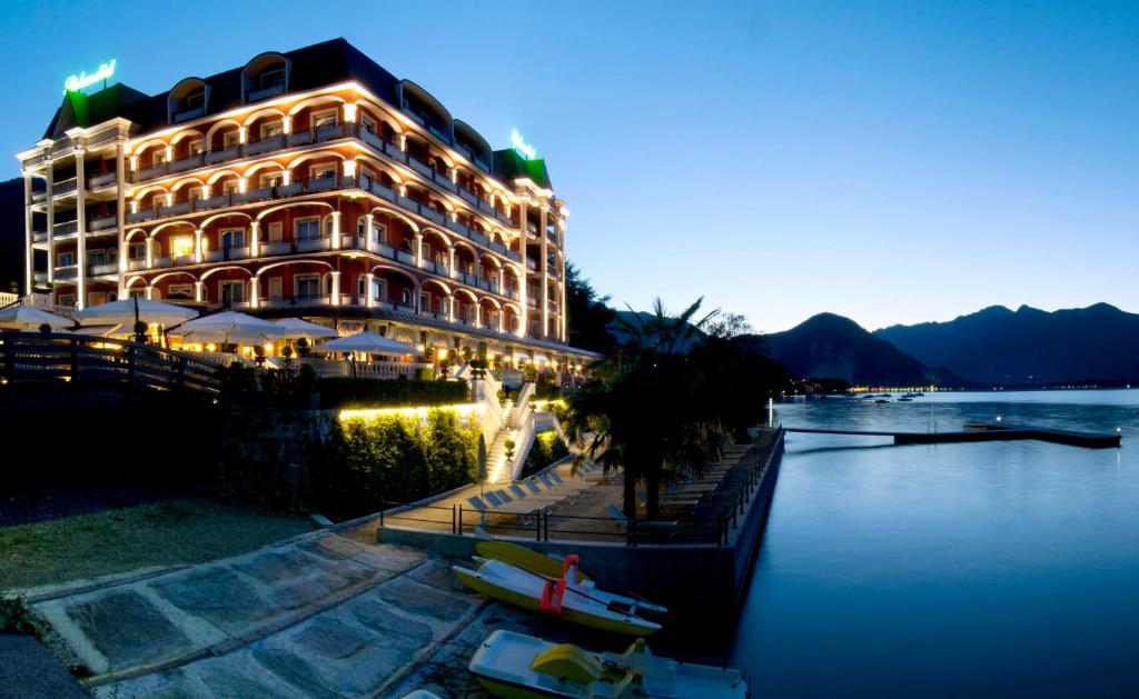 een hotelgebouw met boten in het water 's nachts bij Hotel Splendid in Baveno