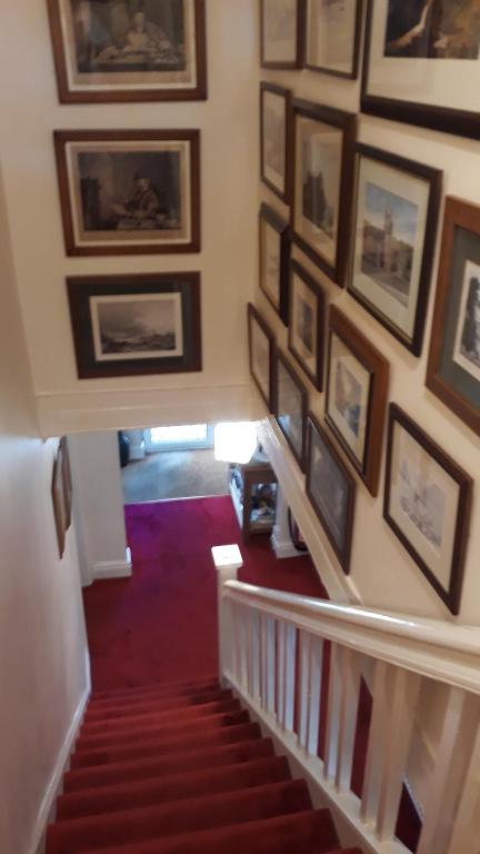 a hallway with a staircase with pictures on the wall at Plas Tirion in Llanddulas