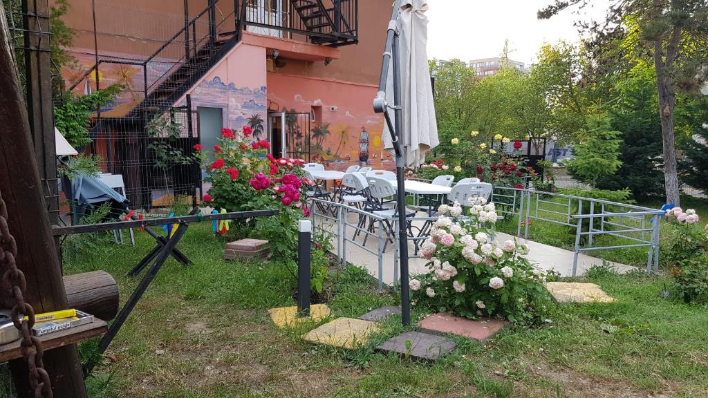 un jardin avec un parasol et des fleurs devant un bâtiment dans l'établissement Hotel-Hostel Mignon Mamaia -private rooms with free parking, à Mamaia