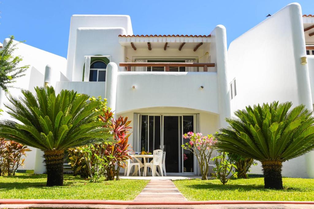 una casa blanca con palmeras delante en Villa Playa Vintage, en Playa del Carmen