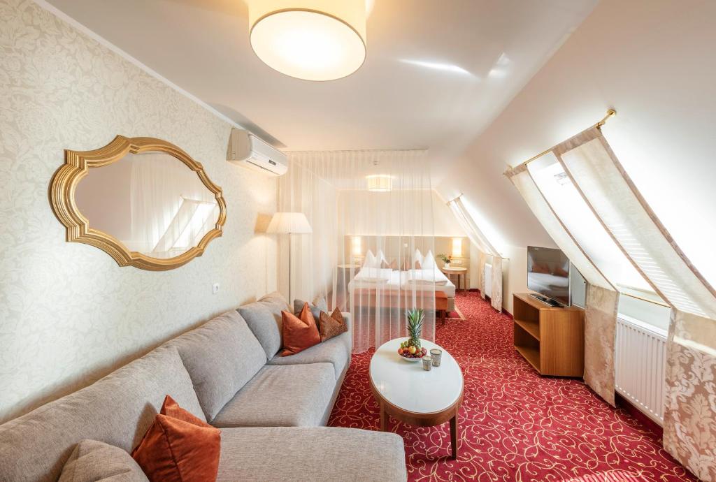 a living room with a couch and a mirror at Hotel Mader in Steyr