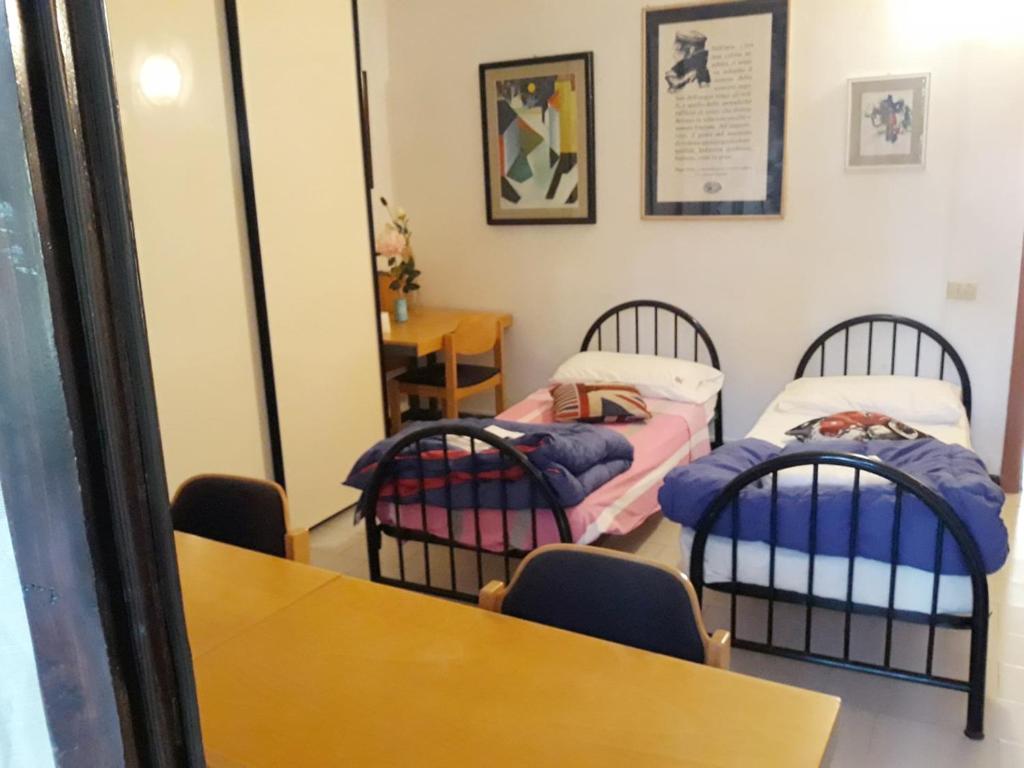 シエナにあるBed in Sienaのベッド2台、テーブル、椅子が備わる客室です。