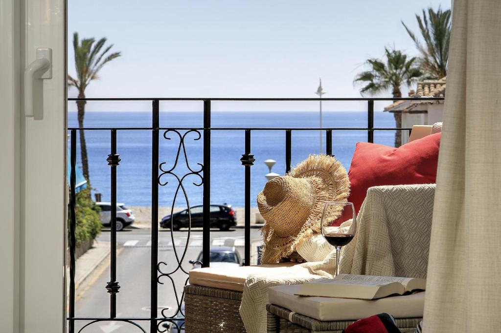 a balcony with a glass of wine and a view of the ocean at Casa de la playa Alto de el Realengo in La Herradura