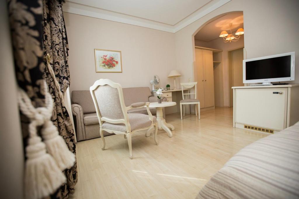 un soggiorno con tavolo, sedie e TV di Hotel Burghof a Hof