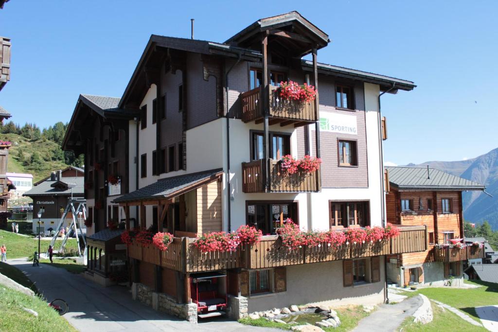 a building with flower boxes and balconies on it at Familienhotel Garni Sporting in Bettmeralp