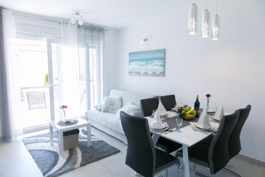 sala de estar blanca con mesa y sofá blanco en Navi, en Kaštela