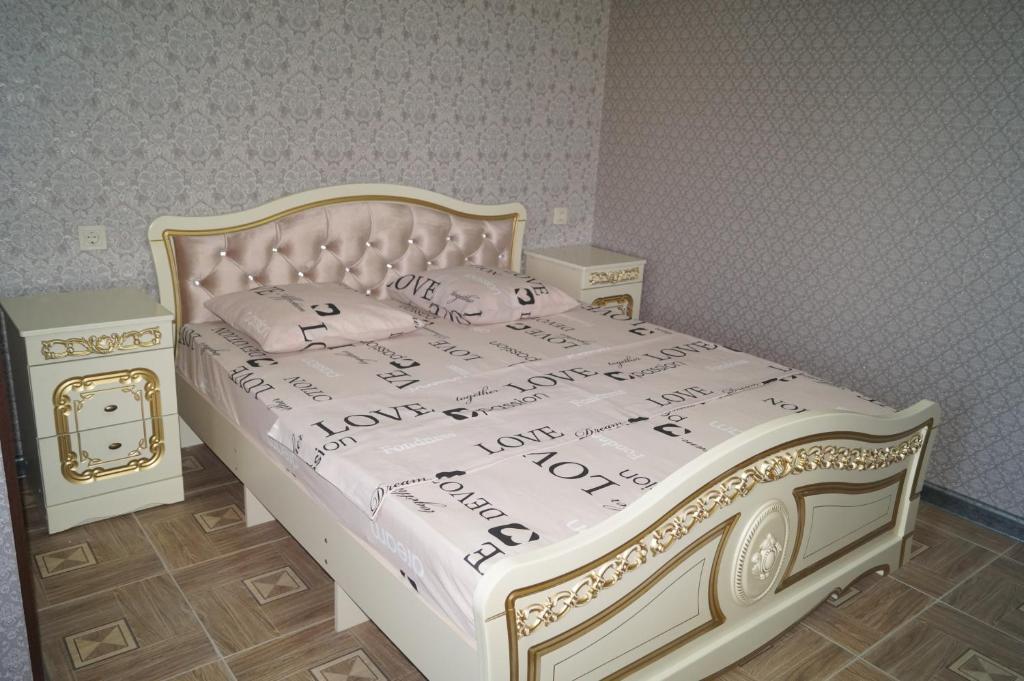 a bedroom with a bed with a white and gold bed frame at Валентина in Gagra