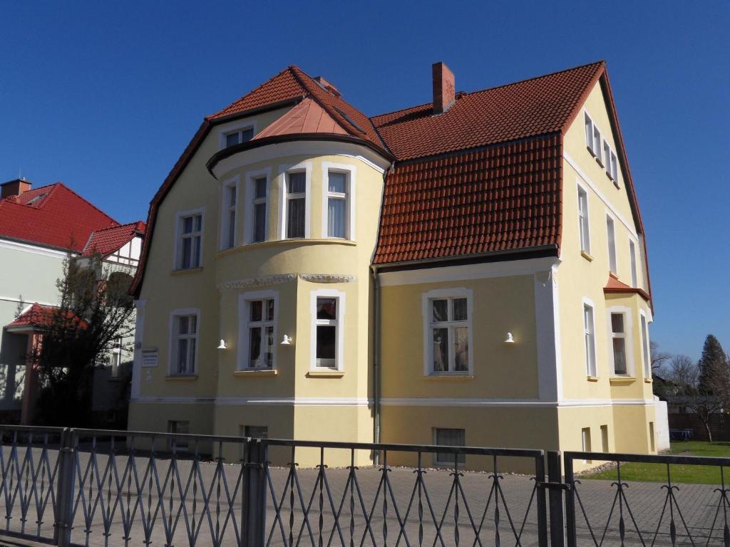 une maison jaune avec un toit rouge dans l'établissement Ferienappartements Rindfleisch, à Stralsund