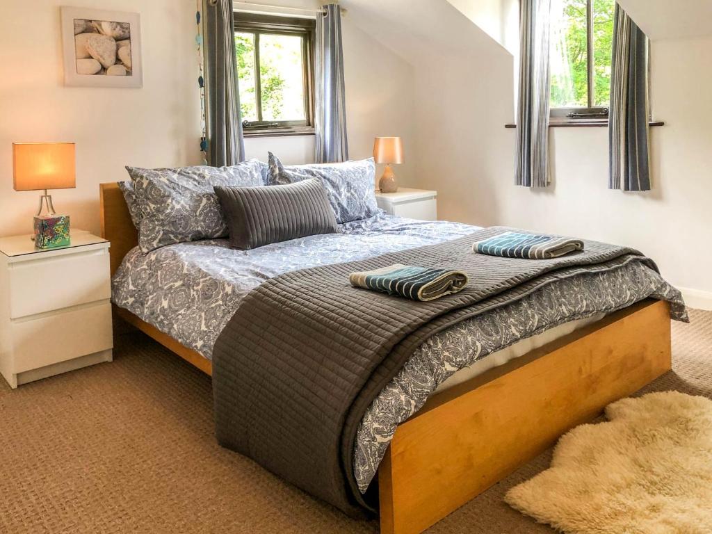 a bedroom with a bed and two windows at THE OLD RECTORY ROSE COTTAGE in Jacobstow 10 mins to Widemouth bay and Crackington Haven,Nearby Bude,Tintagel,Port Issac,Clovelly,PARKING FOR LARGE AND MULTIPLE VEHICLES in Jacobstow