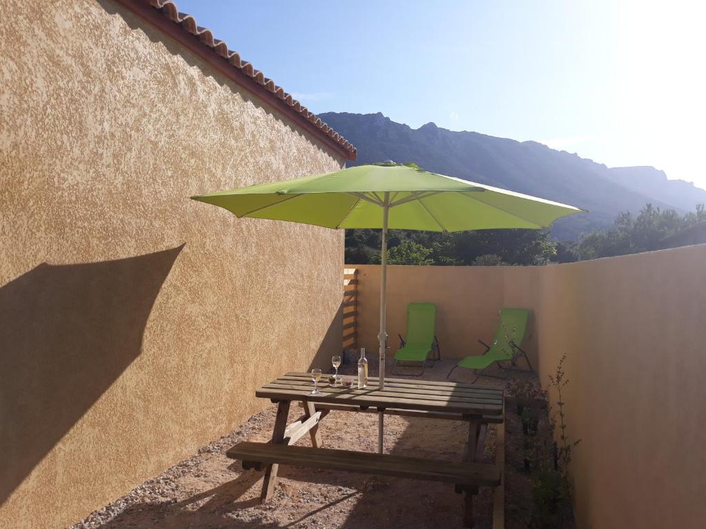 a picnic table with a green umbrella on a patio at Studio les trois chemins in Cucugnan