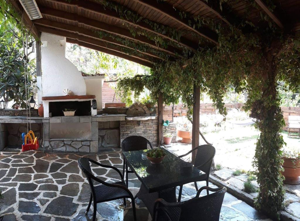 een patio met een tafel en stoelen en een open haard bij THEODORAS HOUSE in Iraklitsa