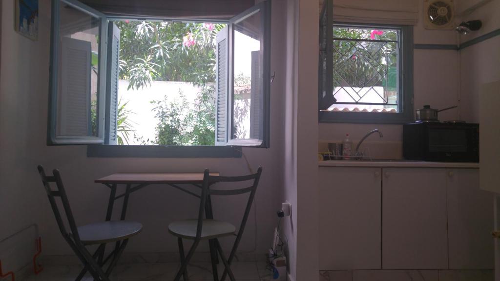 una cucina con tavolo e due sedie e due finestre di Renovated Studio with garden in heart of Athens ad Atene