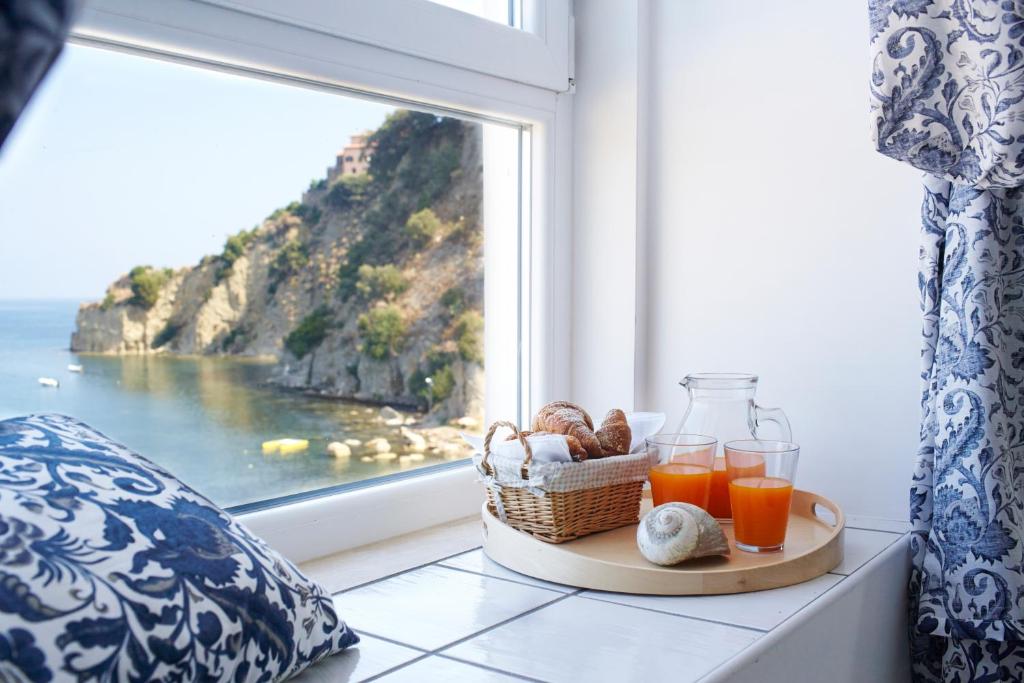 un vassoio con un cesto di pane e succo d'arancia accanto a una finestra di Palazzo Dogana Resort ad Agropoli