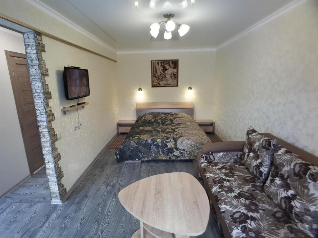 a hotel room with a bed and a couch at Lux Apartment on Mayakovsky 6 in Ustʼ-Kamenogorsk