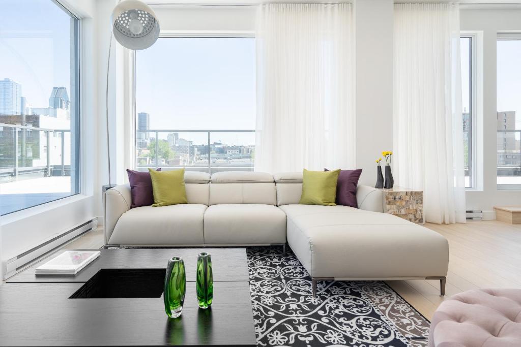 a living room with a white couch and a large window at Le Se7t Penthouses in Montreal
