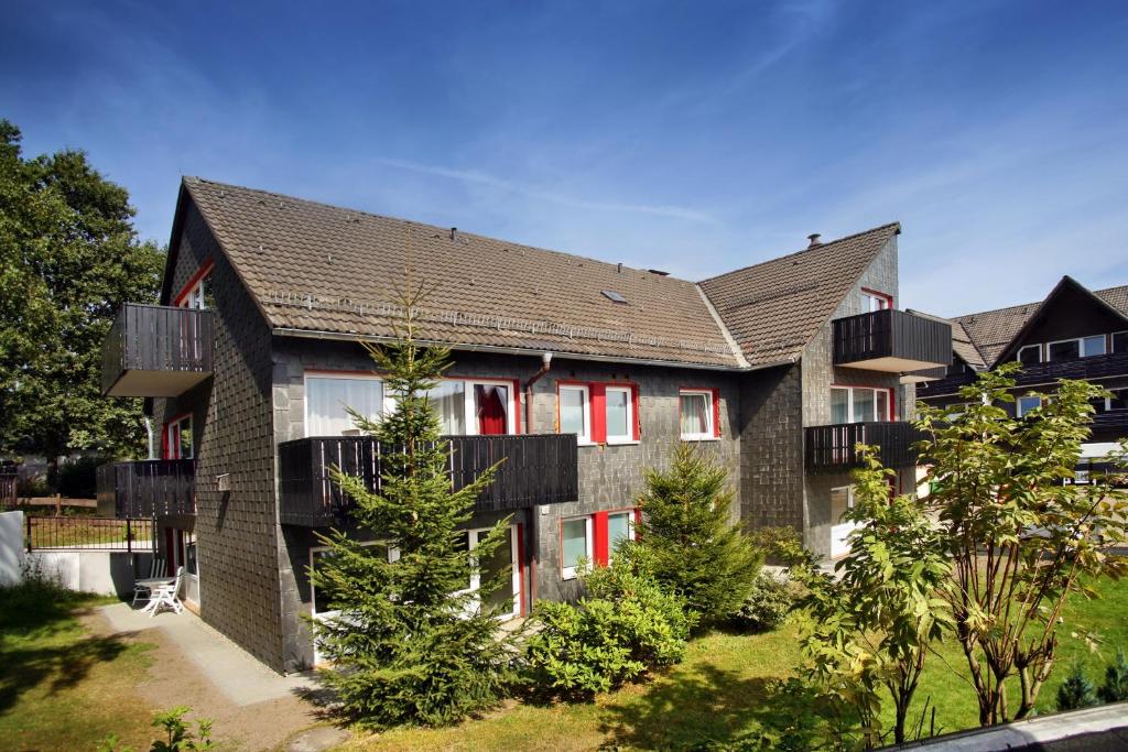 una casa con persianas rojas en las ventanas en Appartementanlage Vierjahreszeiten, en Braunlage