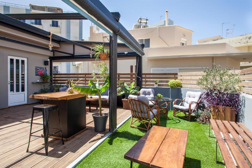 a rooftop patio with wooden tables and chairs and grass at So Young Hostel in Heraklio Town