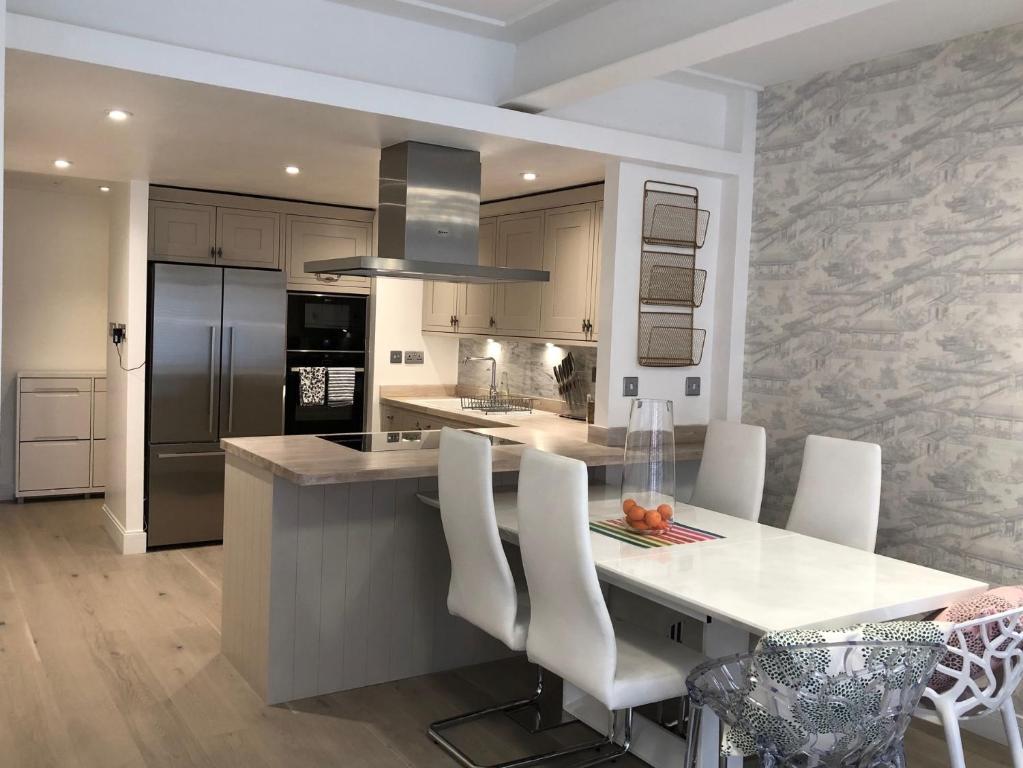 a kitchen with a large island with white chairs at Award Winning 2023 luxury Holiday Rental Apartment Stratford London in London