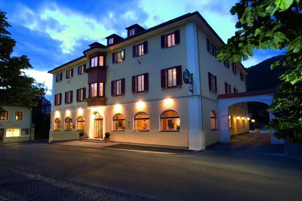 ein großes weißes Gebäude mit Licht an in der Unterkunft Gasthof Goldener Fisch in Lienz