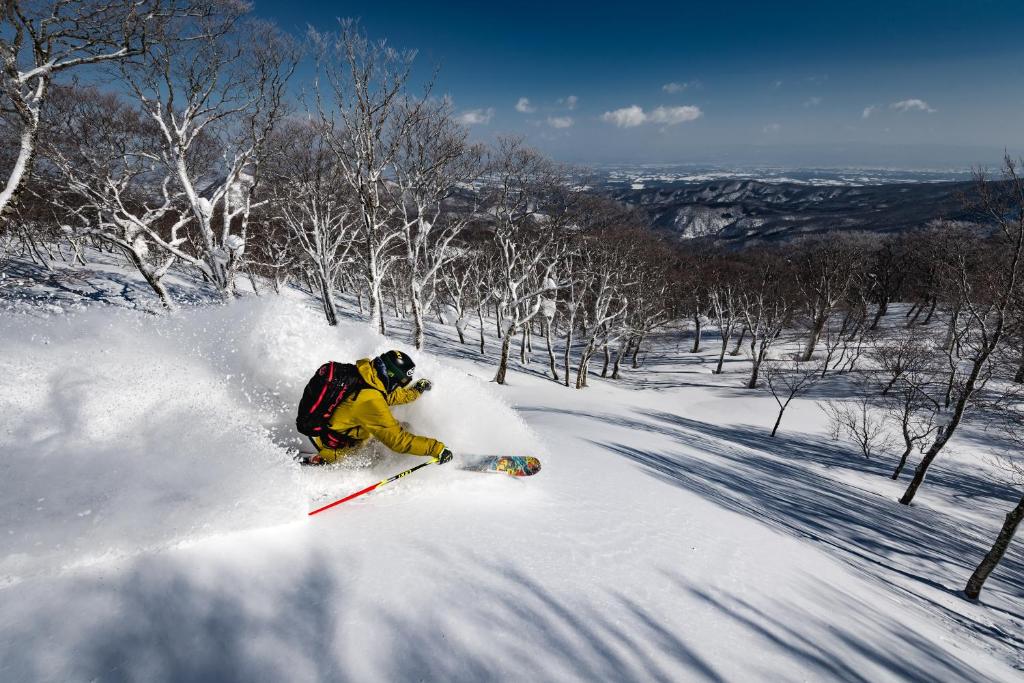 a person is skiing down a snow covered slope at 夏油高原スキー場 in Kitakami