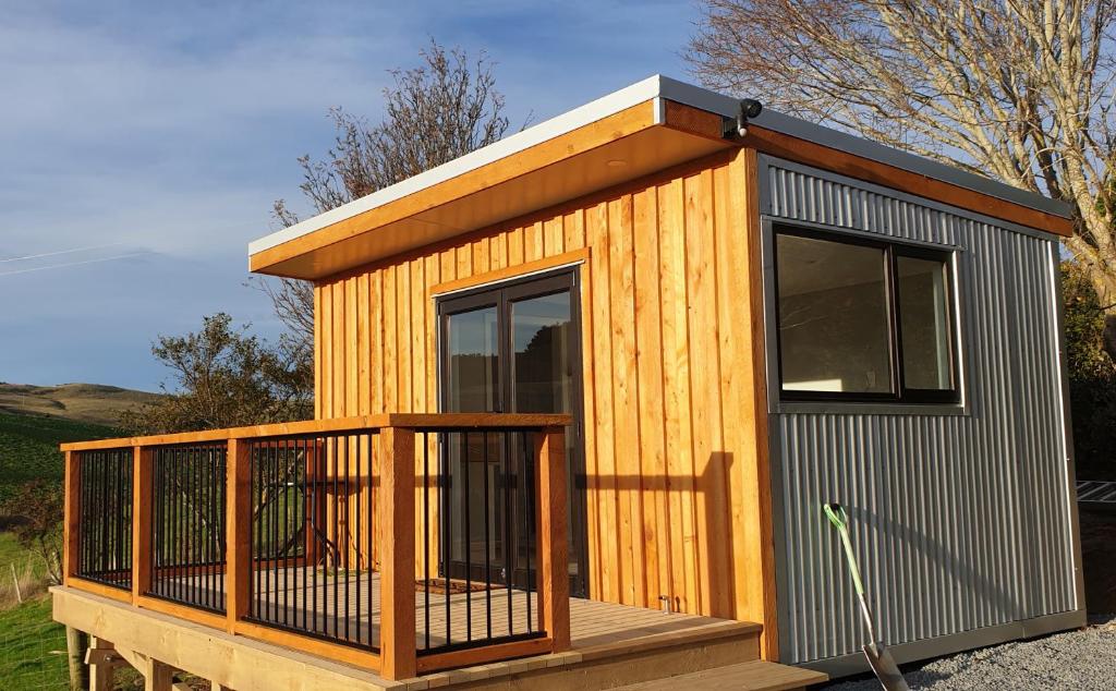 een klein houten huisje met een veranda en een terras bij Lawfield in Glenomaru