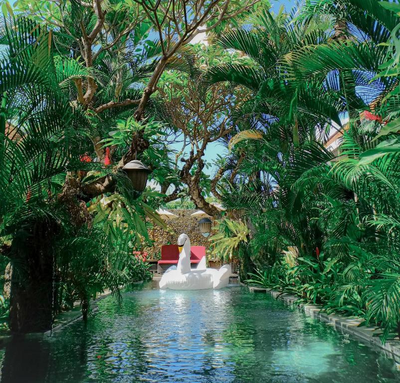 a pool in a resort with a white duck in the water at Uma Karan in Seminyak