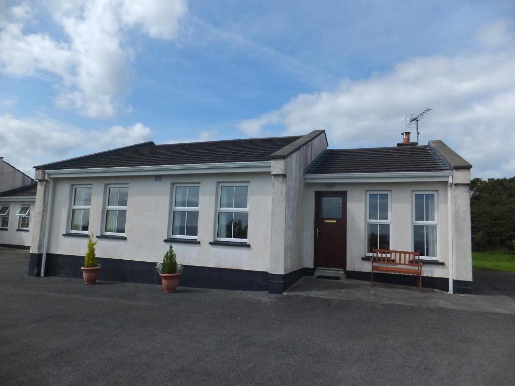 a white house with a bench in front of it at Drumkeeran Holiday Homes in Drumkeeran