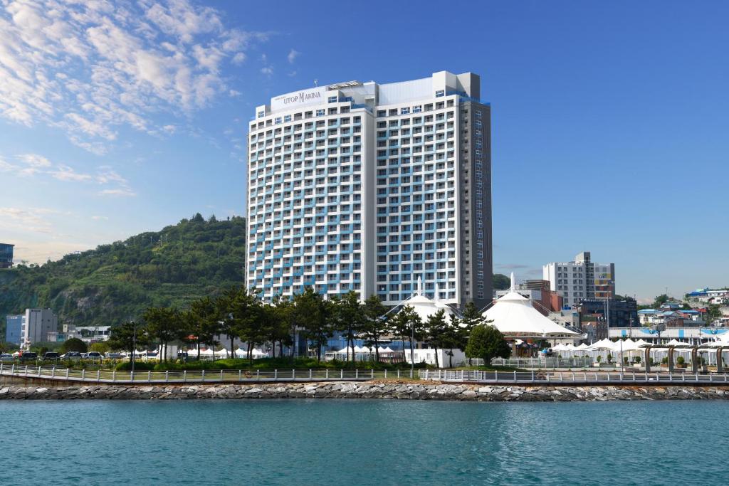 ein hohes Gebäude vor einem Wasserkörper in der Unterkunft Utop Marina Hotel & Resort in Yeosu