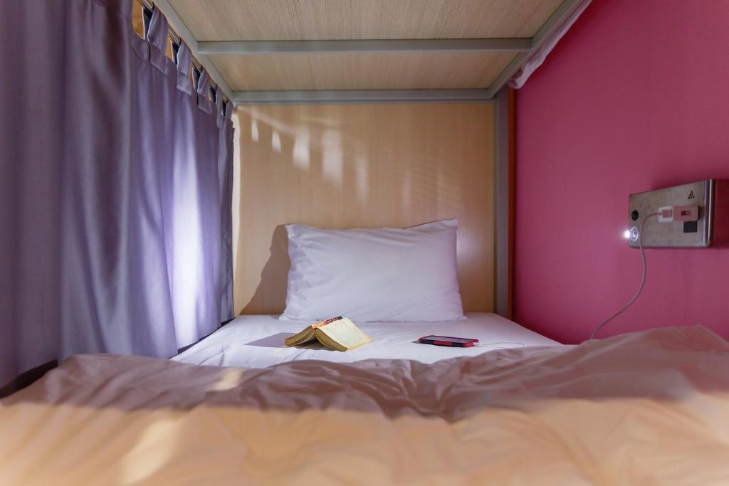 een slaapkamer met een bed met een boek erop bij Siamaze Hostel in Bangkok