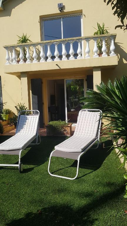 dos sillas blancas sentadas en el césped frente a una casa en Chambre chez particulier pour homme ou couple, en Cannes