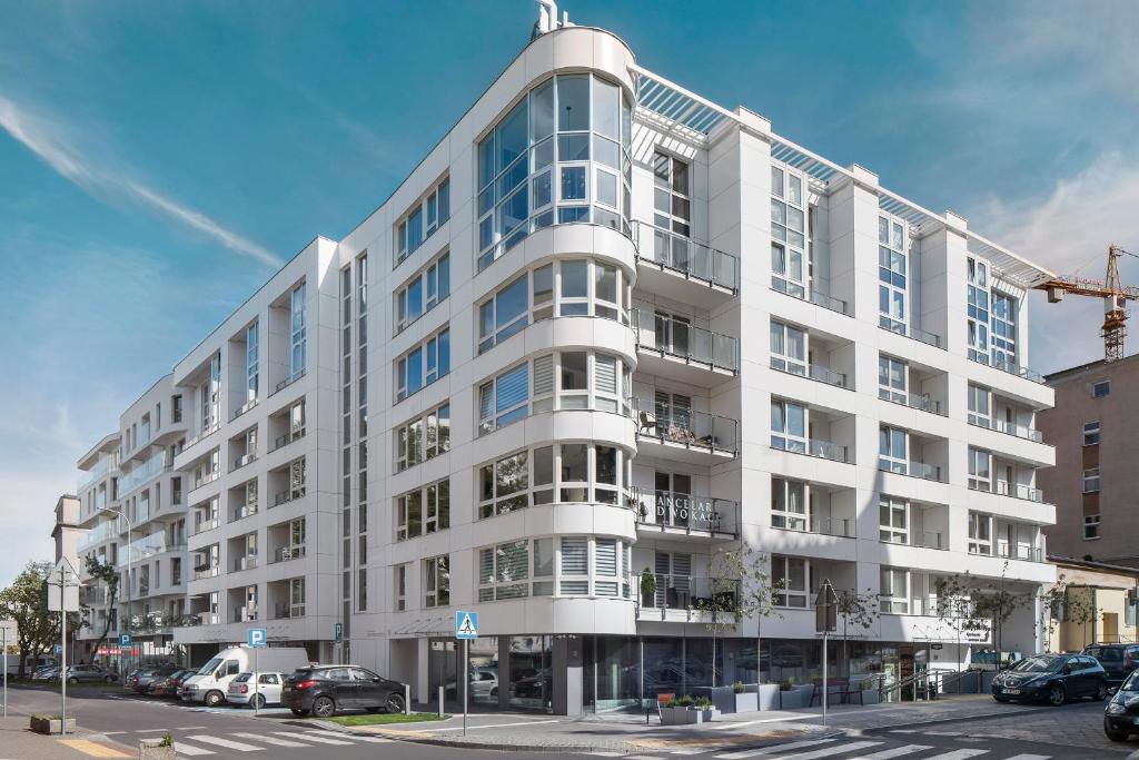 a white building with cars parked in front of it at Sleepy3city Apartments Batorego 9 in Gdynia