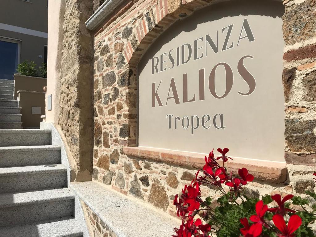 a sign for a restaurant in a building with red flowers at Residenza Kalios in Tropea