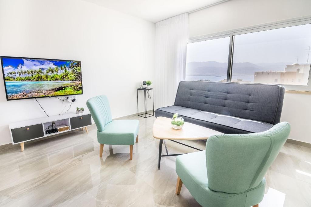 a living room with a couch and chairs and a tv at The suite in Eilat