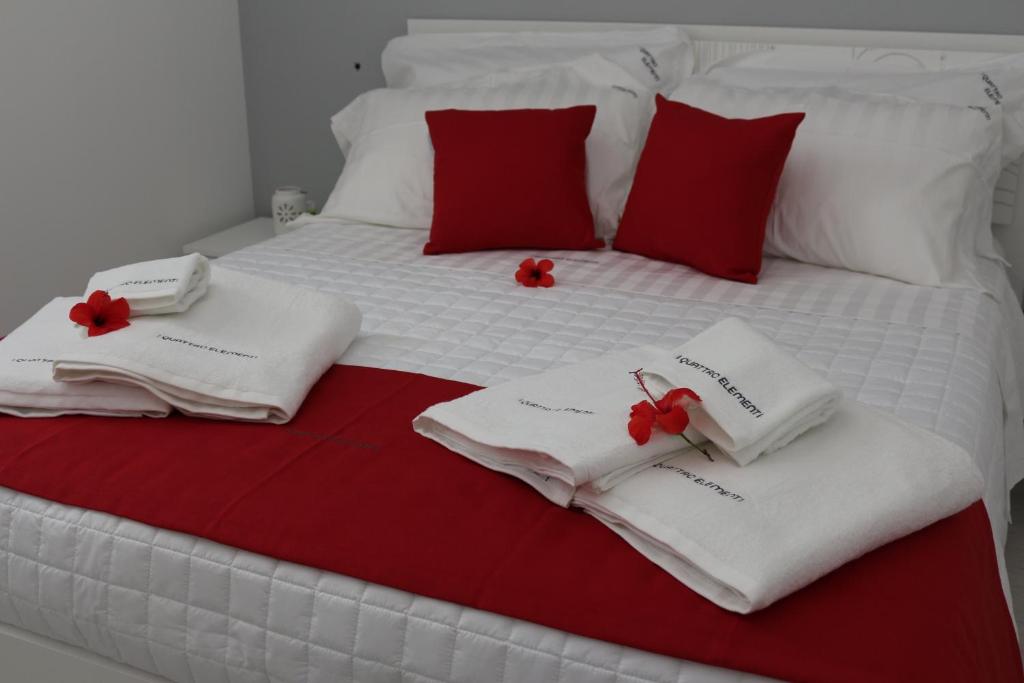 ein Bett mit weißen Handtüchern und roten Kissen darauf in der Unterkunft I Quattro Elementi in Marina di Mancaversa