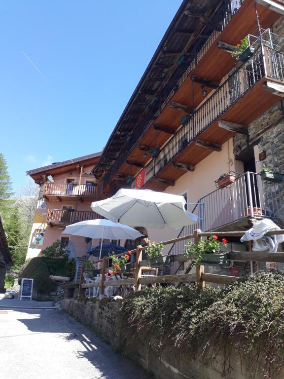 a building with tables and umbrellas in front of it at Relais La Font in Castelmagno