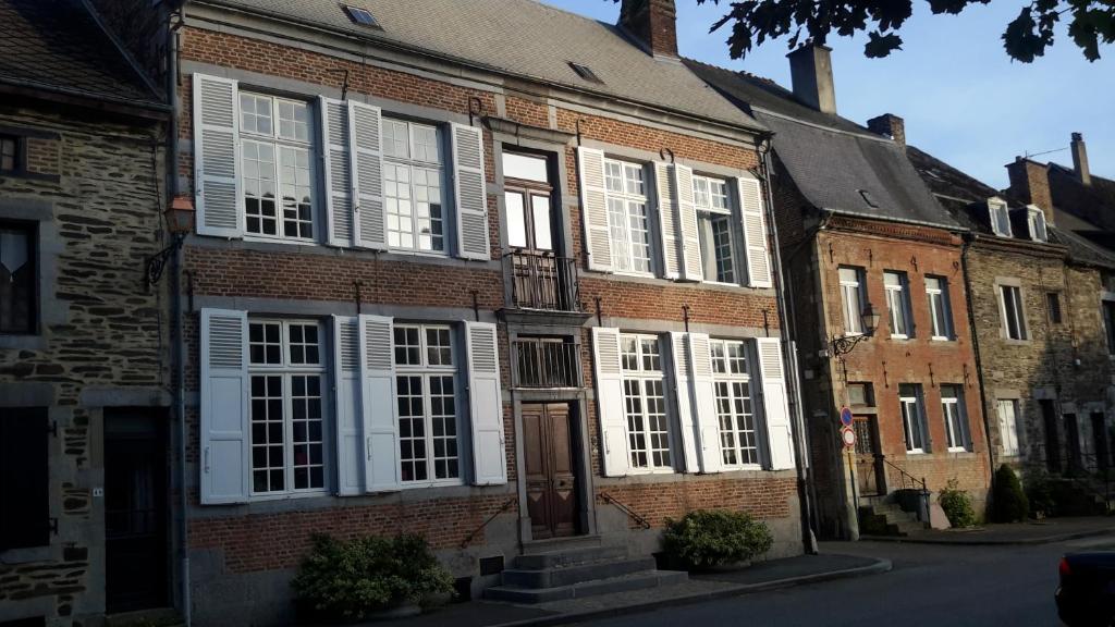 un bâtiment en briques avec volets blancs dans une rue dans l'établissement Huize Carmélites, à Fumay